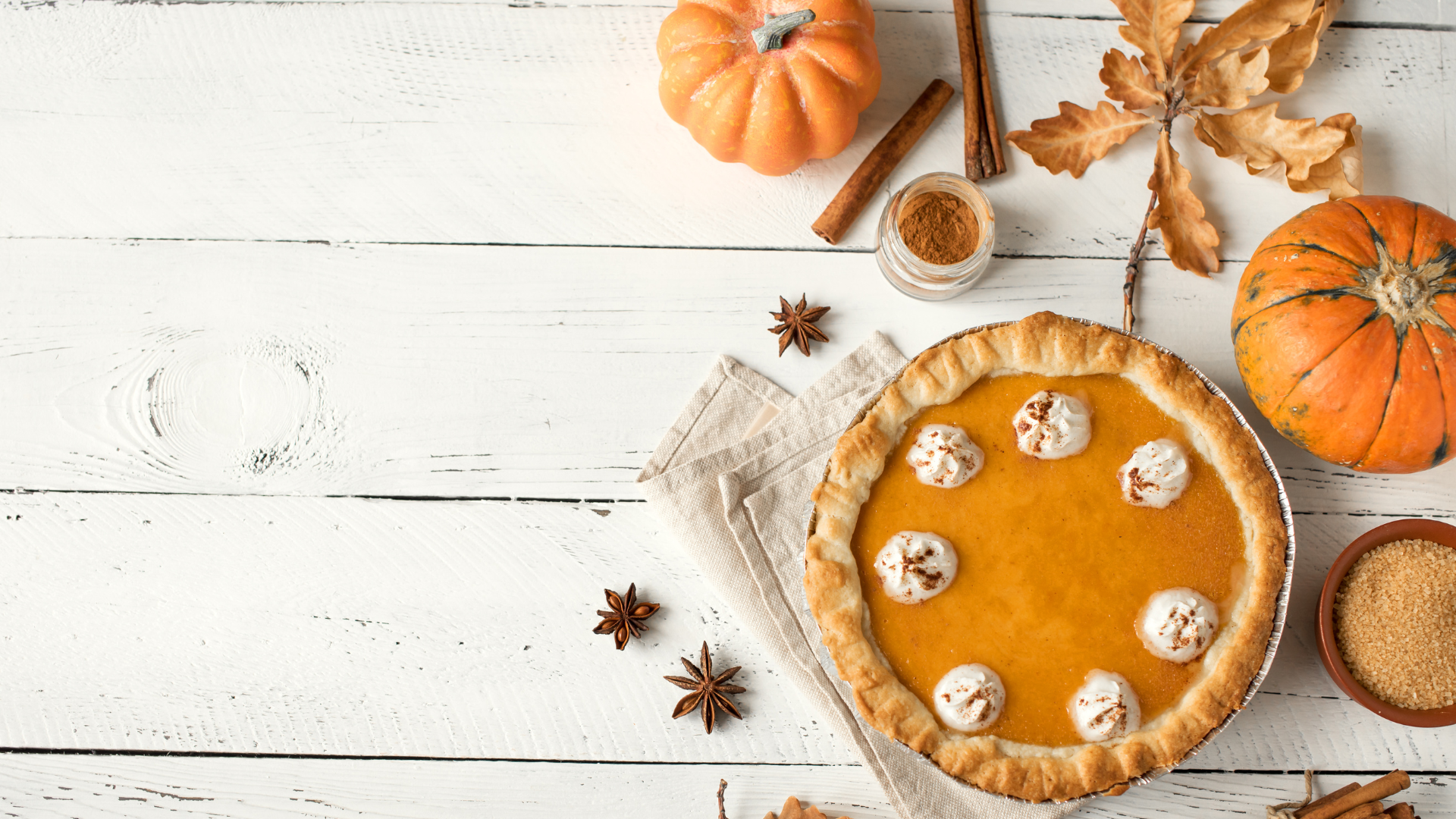 image of wooden table with gourds, autumn leaves and a pumpkin pie on top