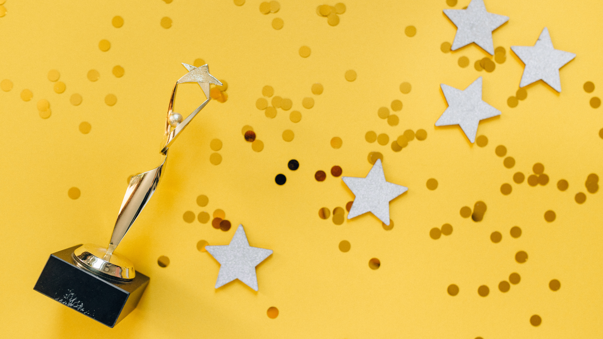 photo of a gold statue and gold confetti stars on a yellow background